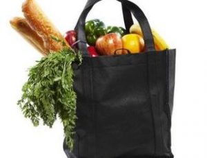 A black reusable grocery bag holding fresh produce