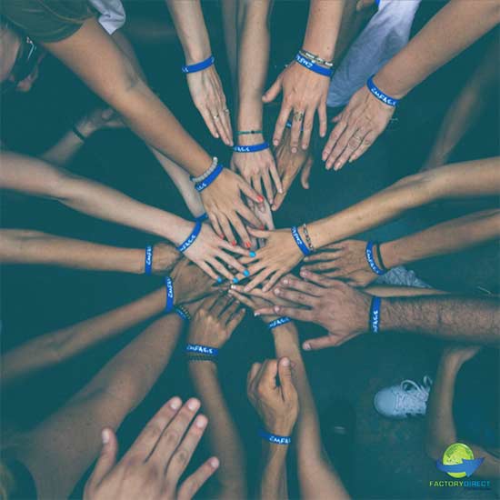 Laying of hands in a huddle with custom blue silicone wristbands