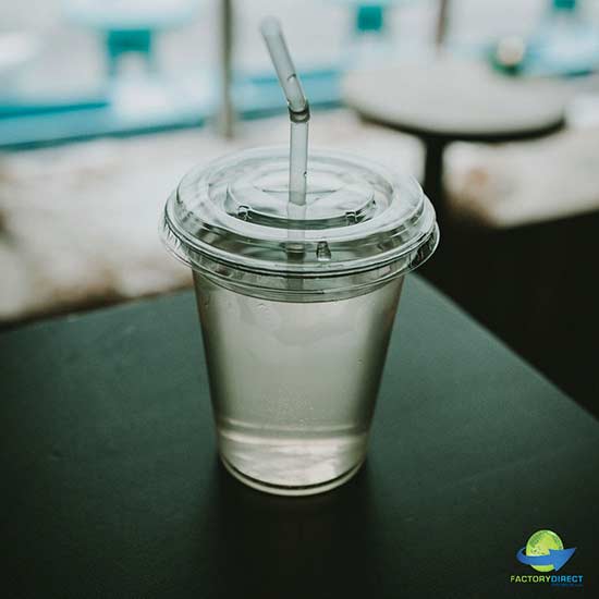 Plastic cup of water with straw on table