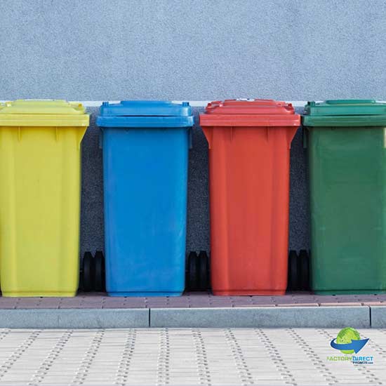 Multi-colored recycling receptacles on a sidewalk curb against a building wall