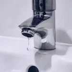 Drip coming out of water faucet into white porcelain sink