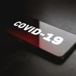 COVID-19 displayed on screen of digital device in low light setting