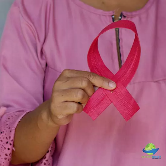 Woman dressed in pink holding a pink ribbon for breast cancer awareness