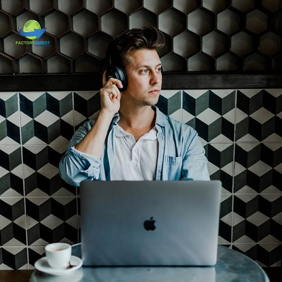 Man with laptop at café listening to headphones