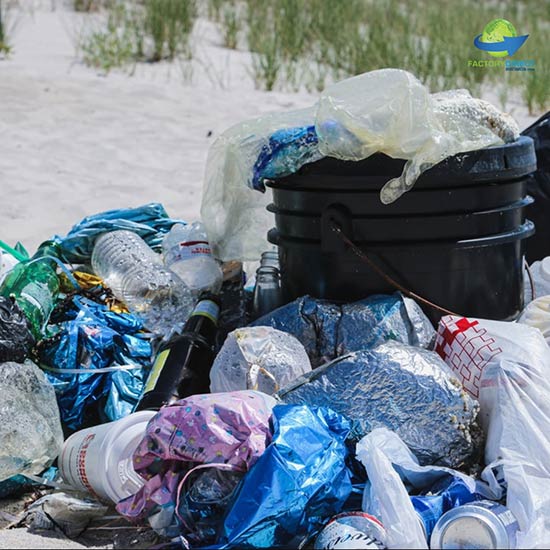 Close-up view of pile of single use plastic products garbage sitting on a sand dune - Beach pollution