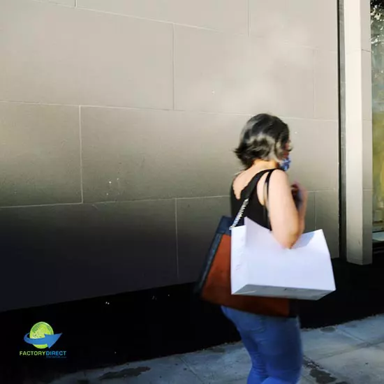 Woman walking outside on sidewalk carrying bags with shoulder straps