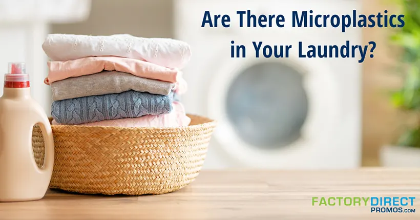 Folded laundry and liquid detergent on a wooden table with washing machine in the background.